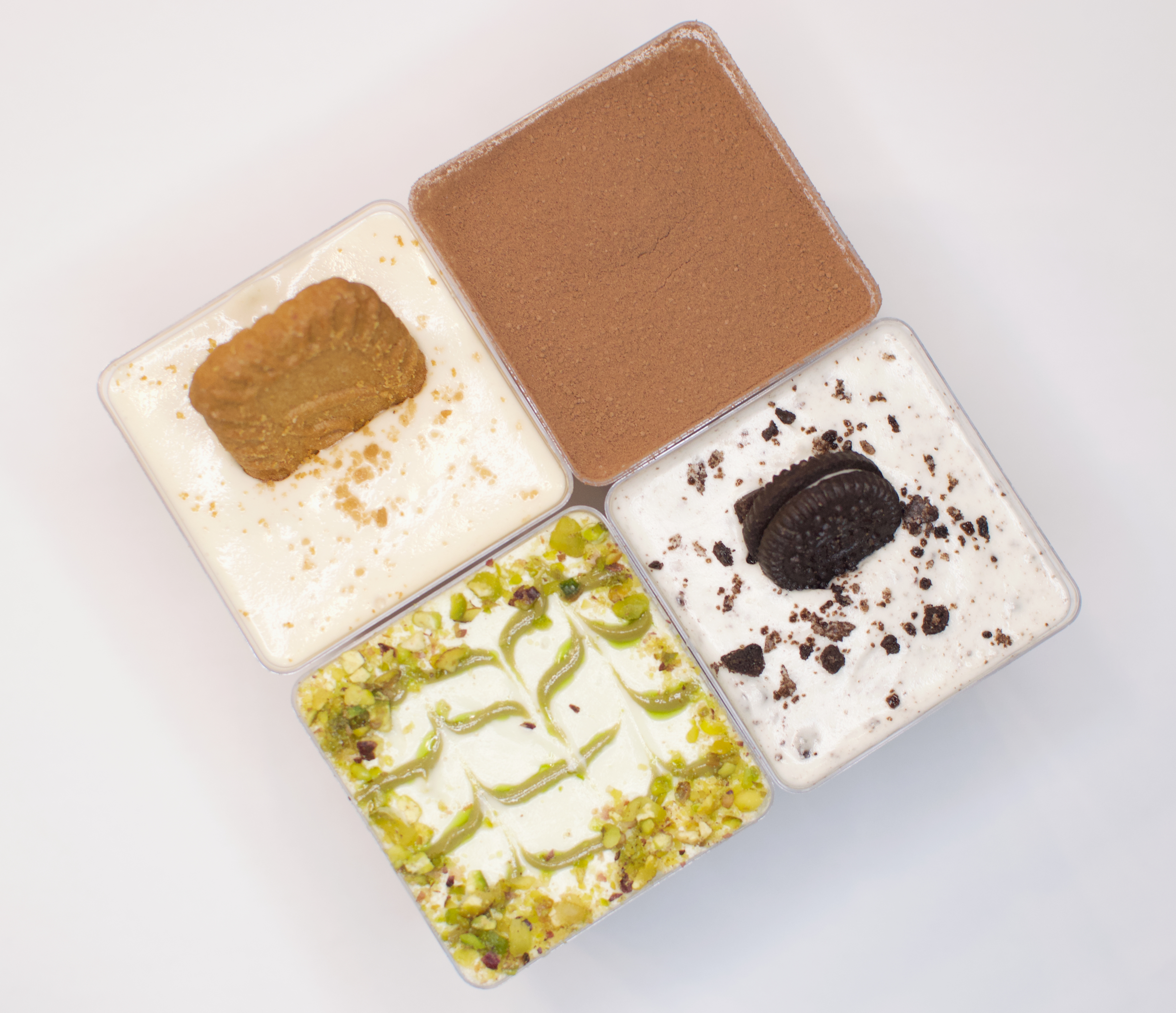 A top-down photo capturing four small square desserts, arranged in a square formation with their corners touching. The gre...